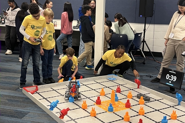 Four Oakland Christian students work hard with their robot on the competition mat.