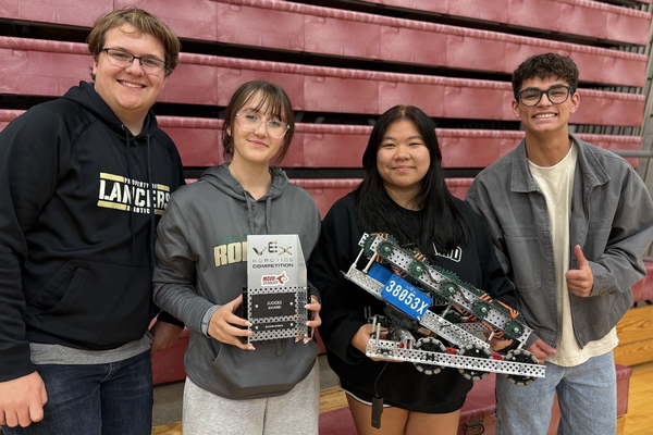 Four smiling Oakland Christian students pose with their robots.