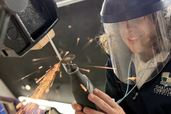 An Oakland Christian student throws sparks using a cutting tool.