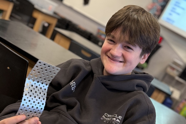 An Oakland Christian student smiles with a building component.