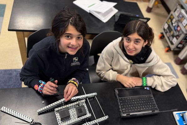 Two Oakland Christian girls work with building components with laptops and tools.