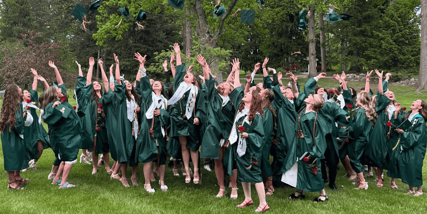 Happy graduates tossing caps outside