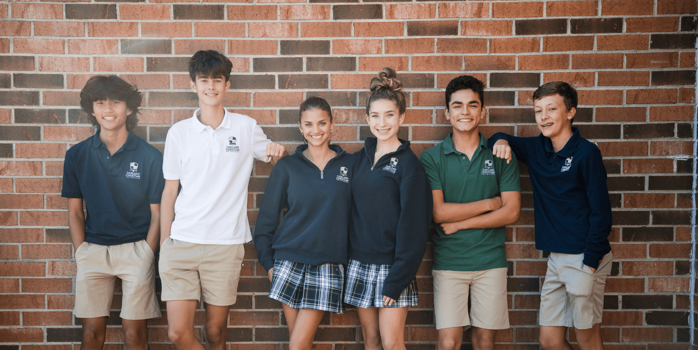 Six secondary students standing outside the brick school building