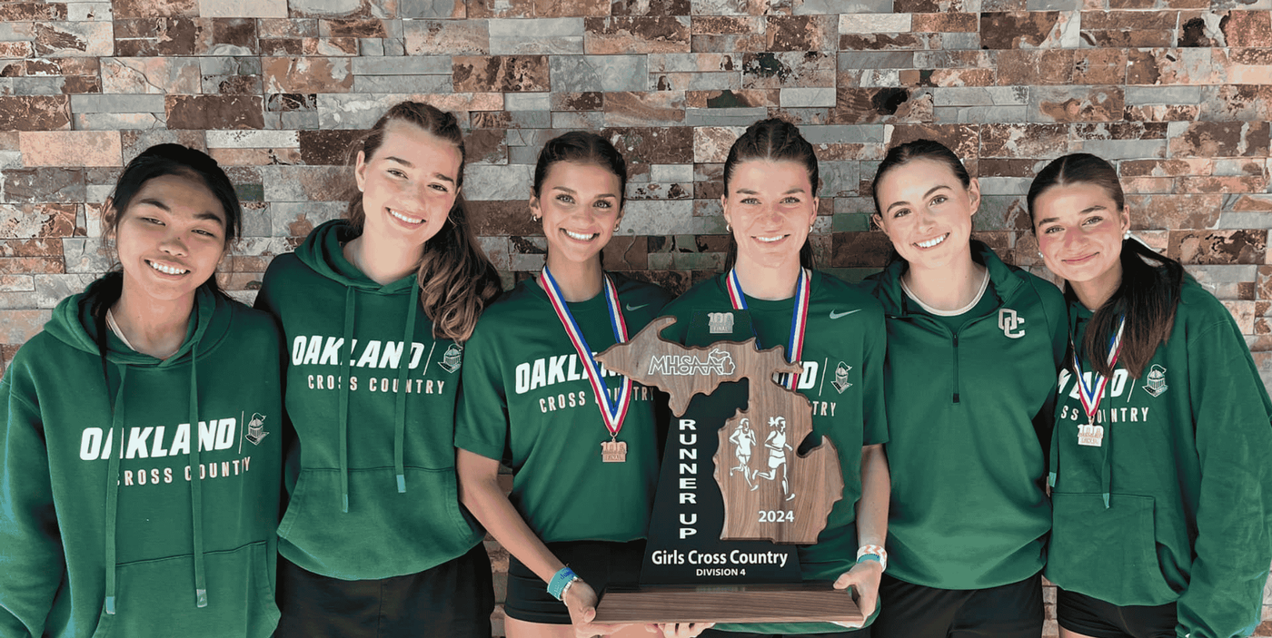 Girls Cross Country team smiling holding a trophy