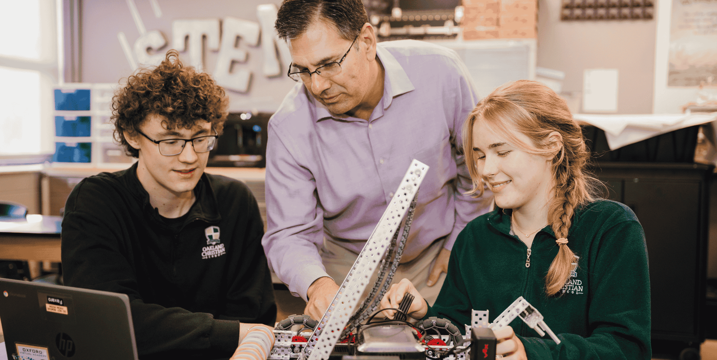 Teacher and two students work on robot