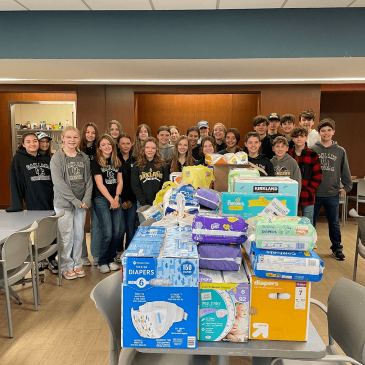 Oakland Christian students pose for a photo by baby diapers, wipes, and other items which were collected for a local ministry.